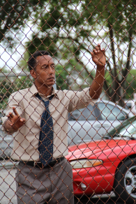 Byrd (Andre Royo) standing by the fence of the basketball court.