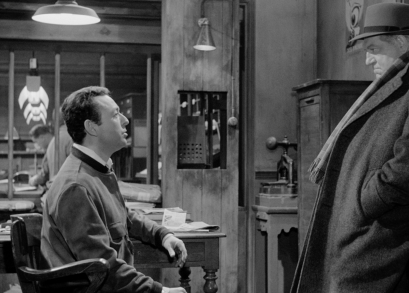 Maigret (Jean Gabin) listens to a newspaper man (Jean-Pierre Granval) in MAIGRET AND THE ST. FIACRE CASE.