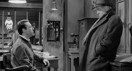Maigret (Jean Gabin) listens to a newspaper man (Jean-Pierre Granval) in MAIGRET AND THE ST. FIACRE CASE.